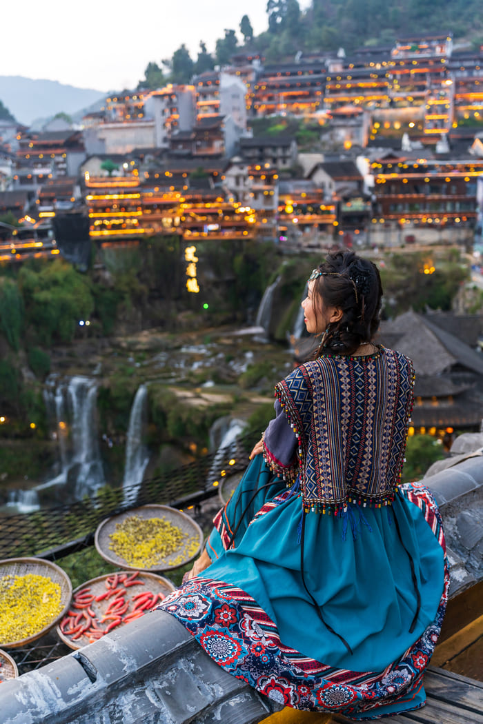 Mujer sentada mirando la ciudad de Lijiang
